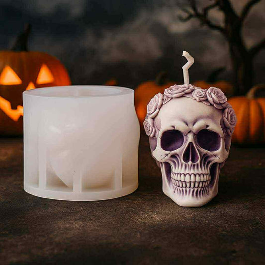 Skull-shaped candle holder with floral crown next to a mold on a dark background with pumpkins.