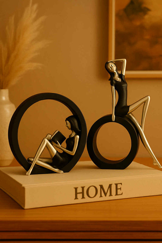 Decorative figurines of a woman reading a book and a man on a bicycle on a 'HOME' book.