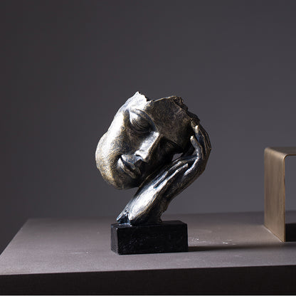 Bronze sculpture of a head on a dark surface with a gray background