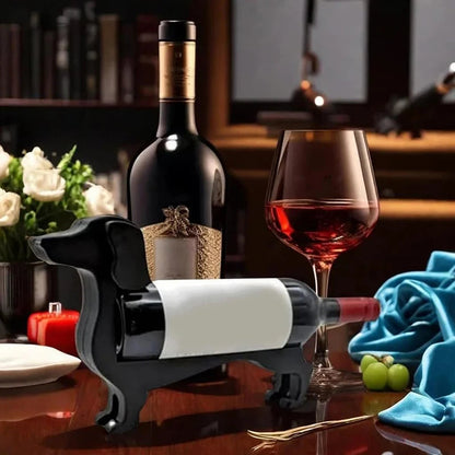 Wine bottle on a stand with a glass of red wine on a table with decorative items.