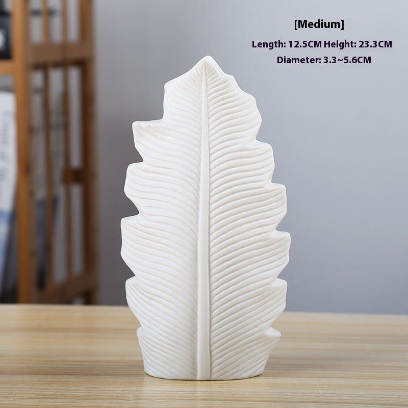 White leaf-shaped decorative item on a wooden surface with measurements displayed.