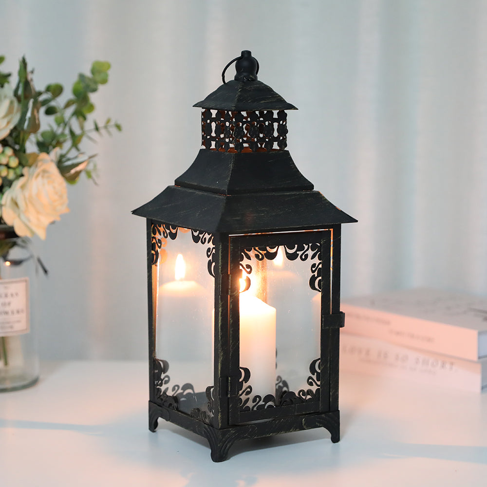 Decorative black lantern with a lit candle inside on a white surface.