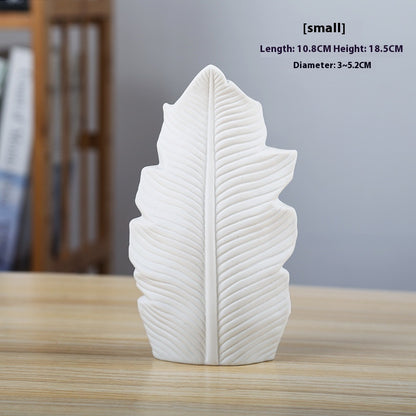 White leaf-shaped vase on a wooden surface with measurements displayed.