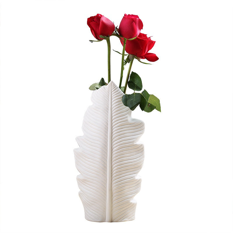 White leaf-shaped vase with red roses on a white background