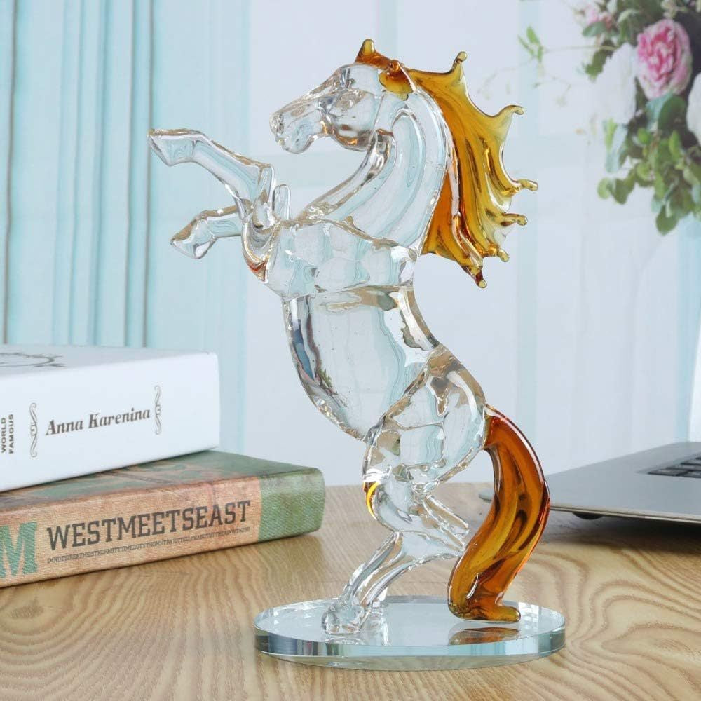 Glass sculpture of a winged figure with amber accents on a wooden surface.