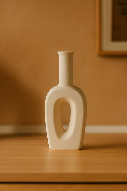 White ceramic vase on a wooden surface with a warm brown background
