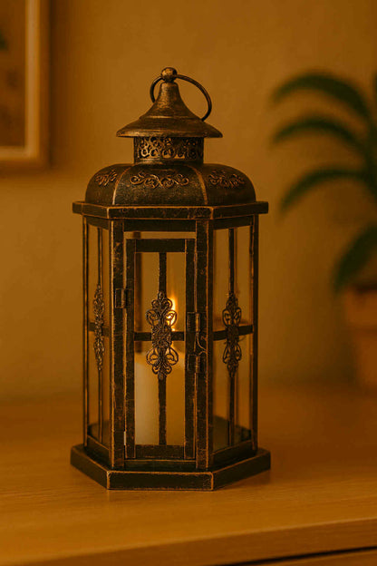 Decorative lantern with a candle inside on a wooden surface.