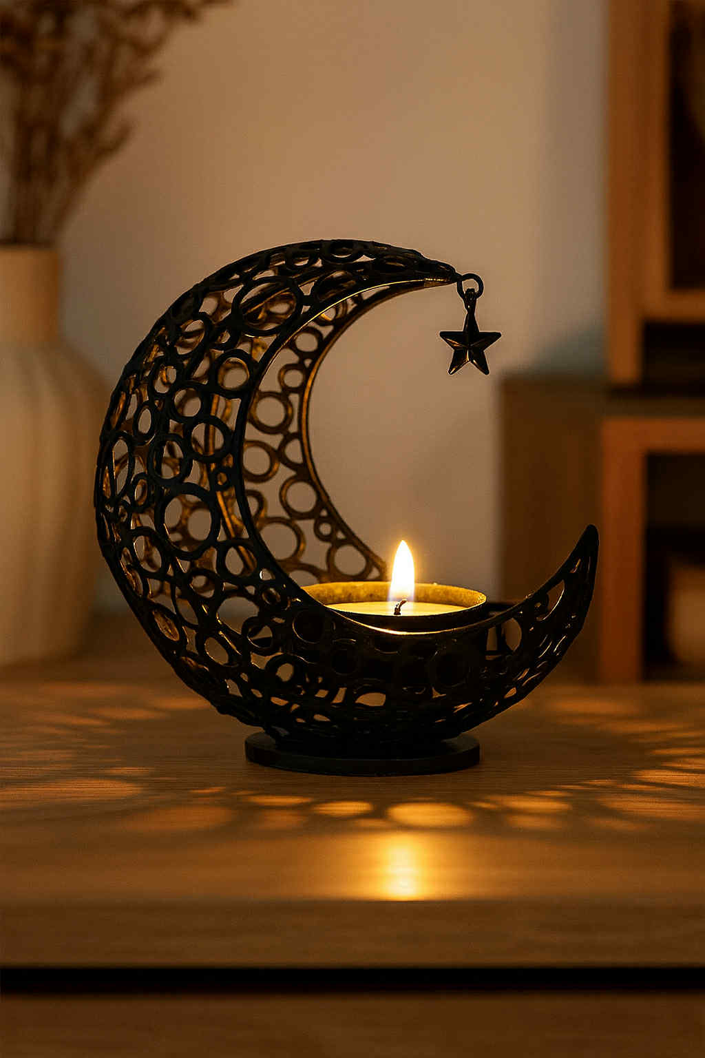 Decorative candle holder shaped like a crescent moon with a star, featuring a lit candle.