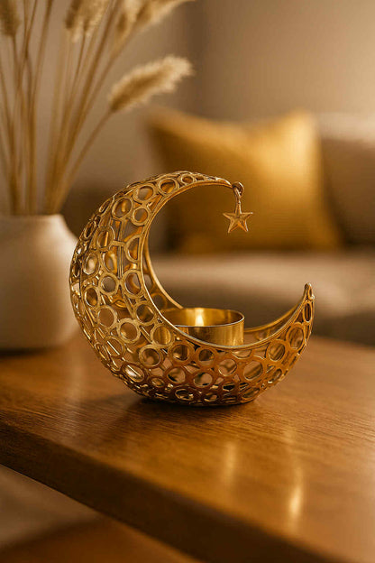 Decorative gold candle holder shaped like a crescent moon with a star on a wooden surface.
