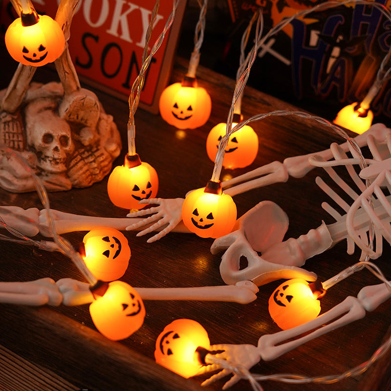 Halloween-themed string lights with skeleton hands and pumpkin design on a dark surface.