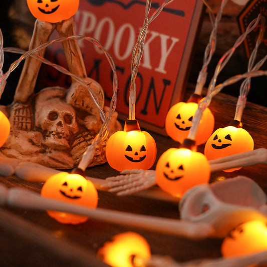 Halloween-themed string lights with jack-o'-lantern bulbs on a decorative setup.