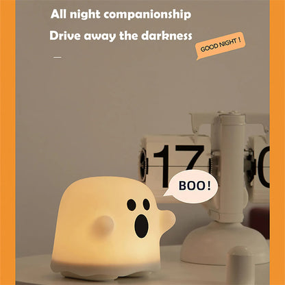 Ghost-shaped night light with 'BOO!' text on a table with a calendar in the background.