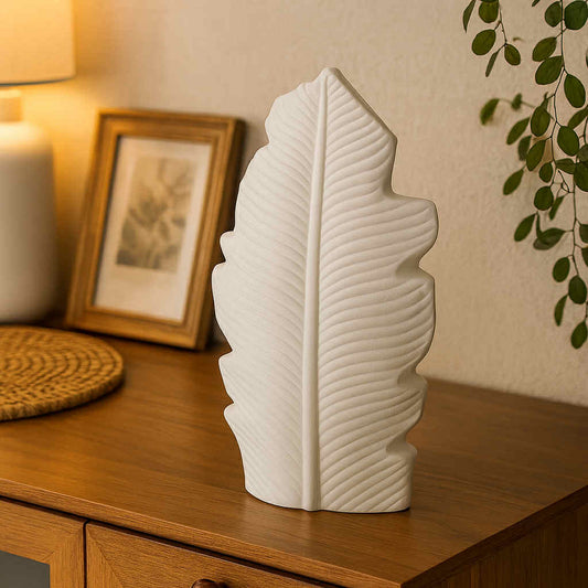 White leaf-shaped vase on a wooden surface with a warm ambiance