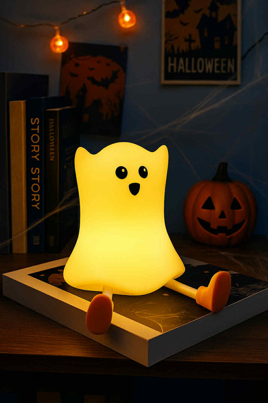 Ghost-shaped night light on a book with Halloween decorations in the background