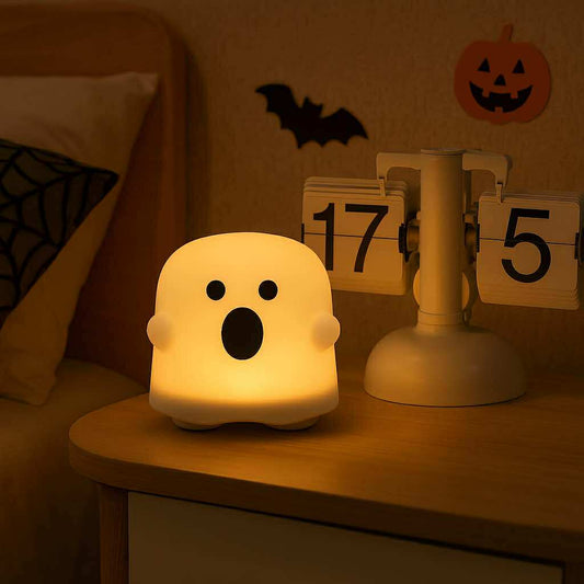 Ghost-shaped night light on a table with Halloween decorations in the background